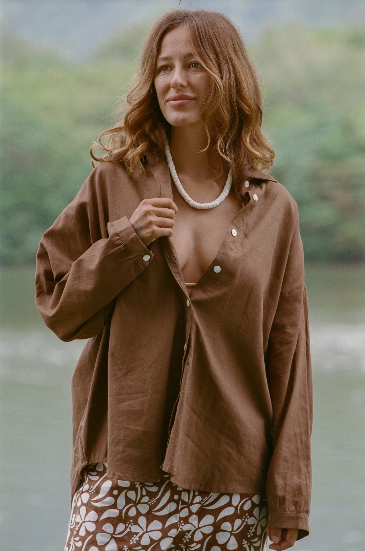 Woman wearing a brown jacket with a blurred natural background
