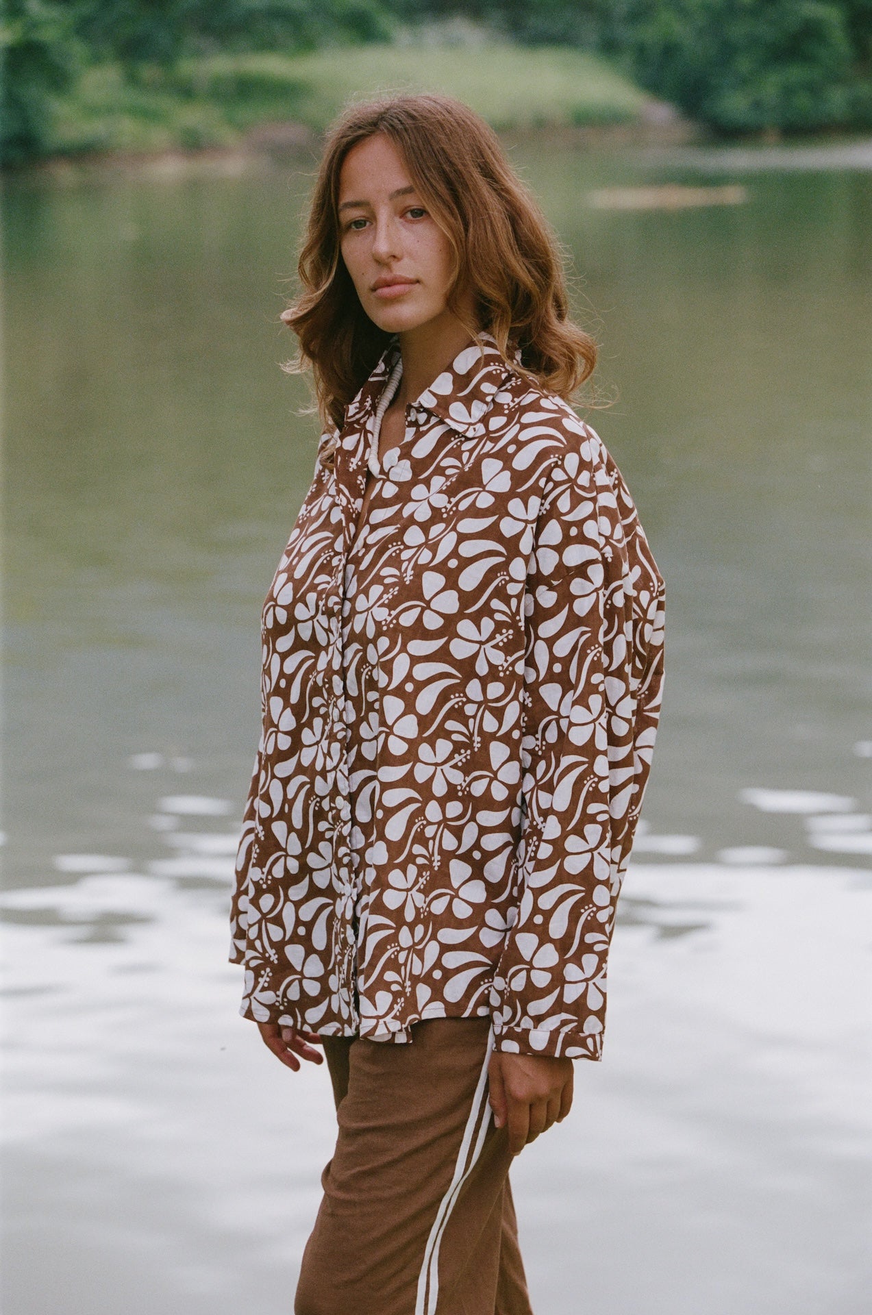 Woman wearing a patterned shirt by a lake